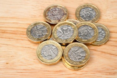 Yeni İngiliz 1 pound sikkelerine yakın çekim, İngiliz sterlin paralarının seçici odak noktası ahşap masa..