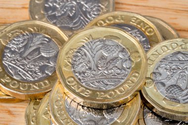 Yeni İngiliz 1 pound sikkelerine yakın çekim, İngiliz sterlin paralarının seçici odak noktası ahşap masa..