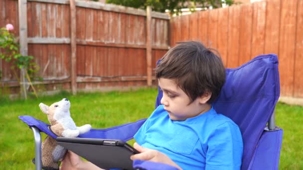 Aktives Kind Sitzt Auf Stuhl Garten Und Spielt Spiel Oder — Stockvideo