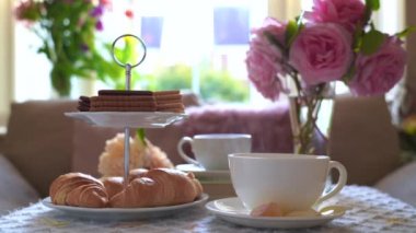 Geleneksel İngiliz çay saati, öğleden sonra çay seremonisi çay, kruvasan, kraker ve bisküvi pembe pastel çay standında. Konservatuar odasında öğleden sonra partisinin samimi havası