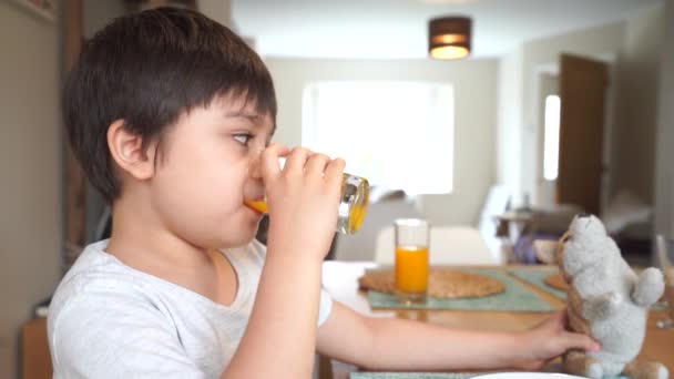 Niño Sano Bebiendo Jugo Naranja Fresco Vidrio Transparente Jugando Con — Vídeos de Stock