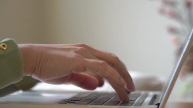 Masada dizüstü bilgisayar kullanan Asyalı bir kadın, evde çalışan klavyeli bir kadın el bilgisayarı, çevrimiçi teknoloji işi, sosyal uzaklık veya E-öğrenme ve çevrimiçi eğitim.  