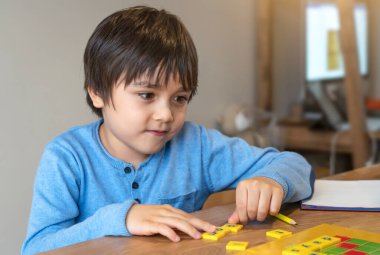Anaokulu öğrencisi İngilizce kelime oyunu öğreniyor, çocuk evde ebeveyniyle İngilizce harf hecelemeye odaklanmış. Uzaklık Eğitimi, çocuklar için etkinlik evde eğitim, yeni normal yaşam tarzı 