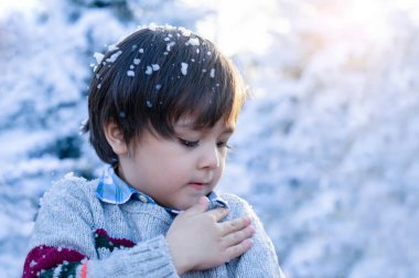 Seçici odaklı şirin çocuk bulanık noel ağacı arka planıyla eline bakıyor çocuk kış fuarında açık havada oynuyor çocuk Noel pazarında kar köpüğüyle eğleniyor.