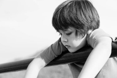 Siyah beyaz oyun parkında yalnız başına duran, üzgün çocuk parkta tek başına oynayan zavallı çocuk, düşünen yüzü yere bakan ve birini bekleyen zavallı çocuk..