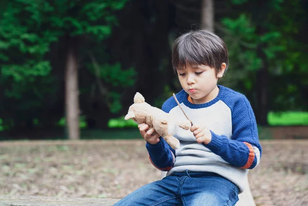 장난감을 앉아서 놀이터에서 막대기 놀이를 아이의 감정적 초상화 소년은 공원에서 — 스톡 사진