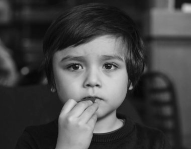 Çikolata yiyen çocuğun siyah beyaz fotoğrafı, düşünce içinde kaybolan küçük çocuğun yüzü çikolata yerken pencereden dışarı bakarken, derin düşüncelere dalmış çocuğun dramatik portresi..