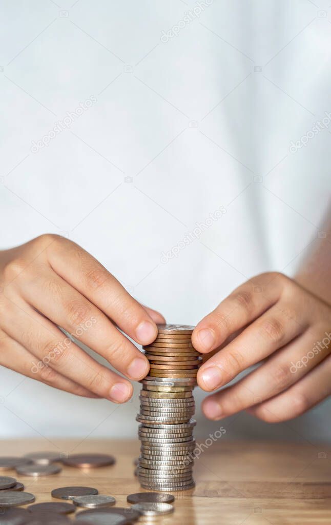 Vertical image Kid hand stacking sterling pound coin and pennies nickels on wooden table with copy space, Financial planing for New Year resolution or saving money for business or life in future
