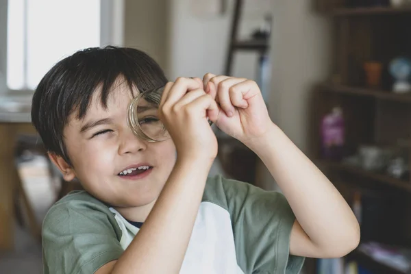 Happy kid looking through glass jar to his experiment. Child boy having fun playing with DIY toy at home, Play and learn at home, environment exploration concept