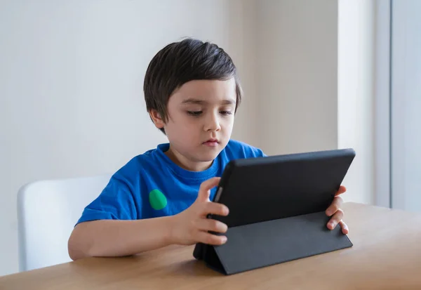 New normal life stlye Kid using tablet  studying homework, Child using digital tablet for his online lesson at home during quarantine, Home schooling, Social Distancing and E-learning online education concept