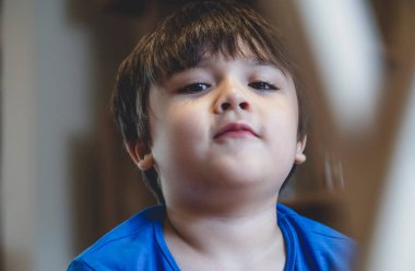 Yüzü bulanık bir çocuk kameraya bakarken komik yüzünü kapatır, gülümseyen yüzlü samimi bir çocuk, evde tek başına oynarken eğlenen yaralı bir çocuk.