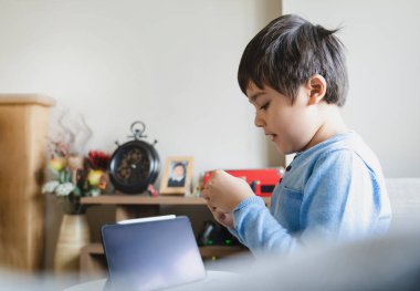 Oturma odasında yalnız oynayan mutlu çocuk portresi, hafta sonları evde dinlenen yeni normal çocuk. Çocuk kavramının pozitif ve mutlu olması