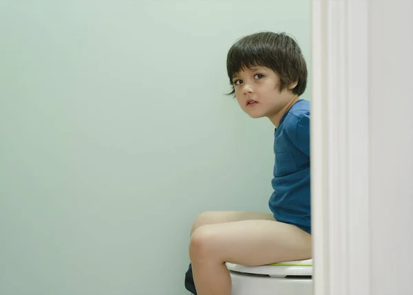 Mutsuz çocuk, midesi ağrıyan bir şekilde tuvalette oturuyor çocuk, evde tuvaleti nasıl kullanacağını, çocuk eğitimini ya da sağlık hizmetleri konseptini nasıl kullanacağını öğreniyor..