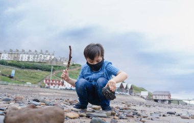 Kirlilik ya da virüs için koruyucu yüz maskesi takan çocuk, Asyalı melez 6 yaşında beyaz çocuk, dışarıda oynarken koruyucu maske takan çocuk, Corona ya da Coronava virüsü için kavram 