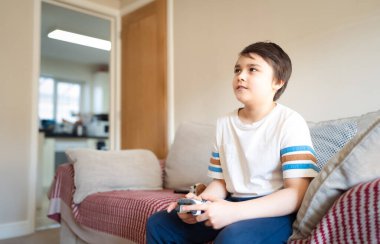 Portre çocuk video oyunu oynuyor. Çocuk evde arkadaşlarıyla konsol oyunu oynuyor, genç çocuk kanepede oturuyor ve hafta sonları tek başına eğleniyor.