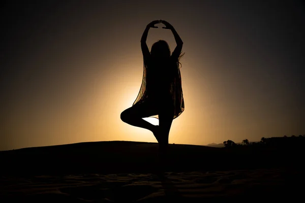美しい夕日の前で踊る姿勢で若い魅力的な女性のシルエット — ストック写真