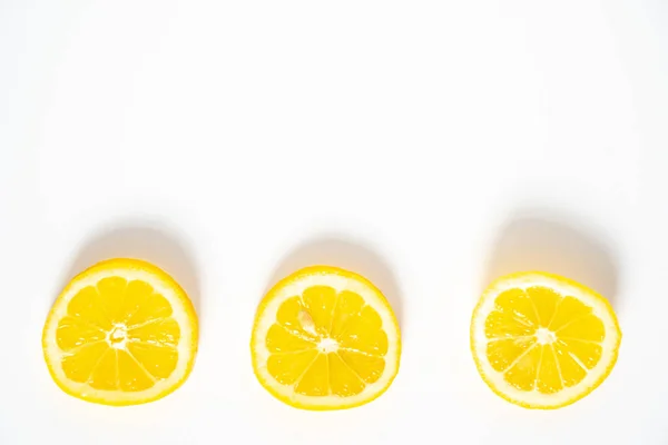 Düz beyaz bir arka planda arka arkaya üç dilim limon.
