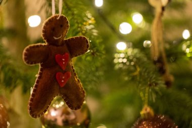 Kumaşlı zencefilli ekmek kadın ayı şekilli Noel ağacı süslemesi bir ağaçtan sarkmış.