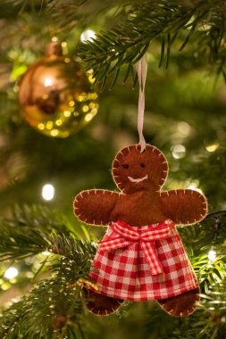 Kumaşlı zencefilli ekmek kadın ayı şekilli Noel ağacı süslemesi bir ağaçtan sarkmış.