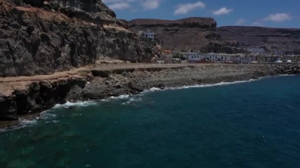 Um drone voando lentamente em direção à costa de uma face de rocha com vista para as ondas batendo contra as rochas — Vídeo de Stock