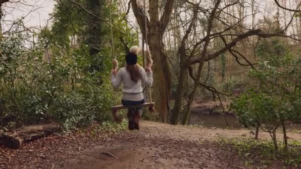 Jeune femme se balançant sur une balançoire faite maison dans les bois 