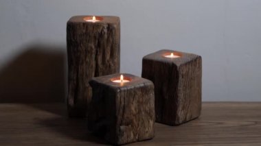 3 ahşap mum tutacağı meşe bir sehpanın üzerinde yanıyor.