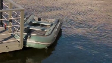 Yeşil şişme bot iskelede demirli. Suyun üzerinde lastik tekne. Balıkçılık teması