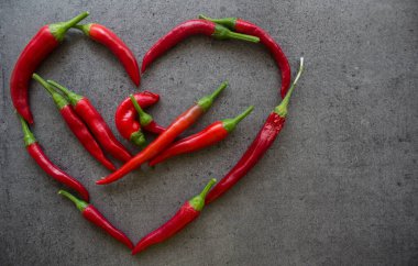 Kalbi kırmızı biberden yapılmış. Taş masada acı biber. Fotokopi alanı olan koyu gri bir arkaplan. İçindekiler üst görünüm fotoğrafı. Sebze dokusunu kapat.. 