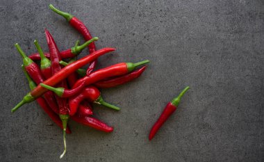 Taş masada kırmızı biber. Fotokopi alanı olan koyu gri bir arkaplan. İçindekiler üst görünüm fotoğrafı. Sebze dokusunu kapat.. 