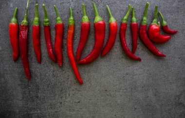 Kırmızı biberler taş masanın üstünde. Fotokopi alanı olan koyu gri bir arkaplan. İçindekiler üst görünüm fotoğrafı. Sebze dokusunu kapat.. 
