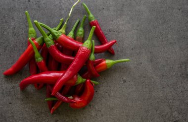 Taş masada kırmızı biber. Fotokopi alanı olan koyu gri bir arkaplan. İçindekiler üst görünüm fotoğrafı. Sebze dokusunu kapat.. 