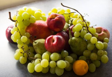 Koyu gri masada güzel taze meyveler: yeşil üzümler, nektarinler, kayısı. Yaz meyveleri üst görünümü. 