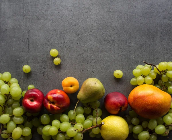 テーブルの上に美しい夏の果物 ジューシーなネクタリン 緑のブドウと梨のトップビューの写真 暗い灰色の背景とコピースペース — ストック写真