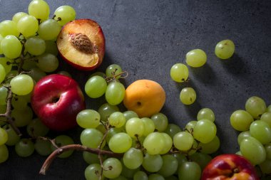 Masadaki güzel yaz meyveleri. Sulu nektarlar, yeşil üzümler ve armut armutları. Kopyalama alanı olan koyu gri arkaplan.