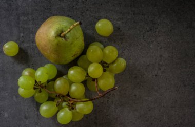 Yeşil armut ve üzümlü, koyu gri desenli arka planda bir hayat. Yaz meyveleri fotoğrafı kapatın.. 