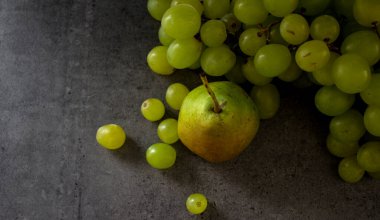 Yeşil üzümler ve armutlarla dolu bir hayat. Koyu gri desenli arka plan. Taze yaz meyveleri üst görünüm fotoğrafı.