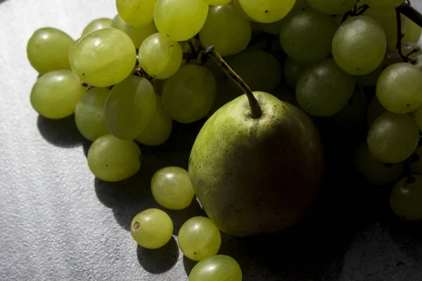 濃い灰色の質感の背景に緑の梨とブドウとまだ生活 夏の果物が閉じ写真 — ストック写真