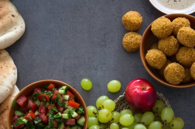 Ortadoğu 'nun otantik yemekleri. Bir tabak humus, falafel, pide, harissa sosu, tahini, taze salata ve meyve. Geleneksel İsrail yemekleri. Renkli yemek resmi.