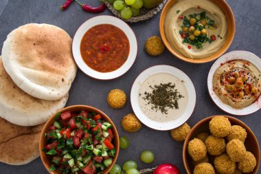 İsrail 'in otantik yemekleri. Farklı geleneksel yemeklerin en üst görüntüsü: taze falafel, bir tabak humus, salata kasesi ve meyve.. 