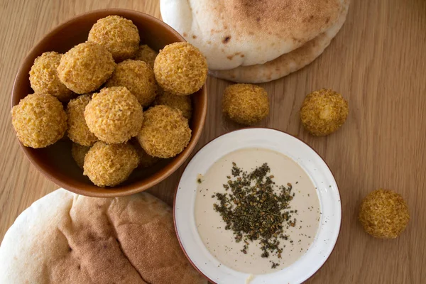 Authentic food of Middle East. Plate of hummus, falafels, pita bread, harissa sauce, tahini, fresh salad and fruits on wooden table. Traditional meals of Israel top view photo. Beautiful food picture with copy space.