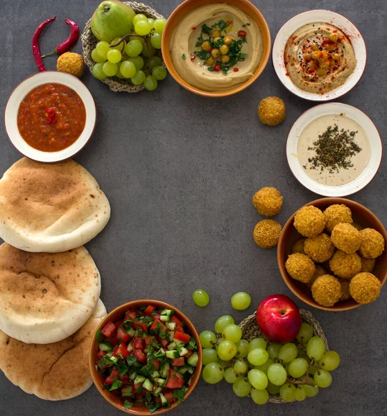 Food frame or border made of traditional meals of Israel. Top view photo of hummus, falafels, pita bread, tahini sauce and fresh fruits. Healthy eating concept.