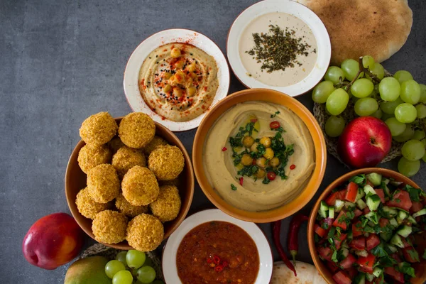 Authentic food of Israel. Top view photo of different traditional meals: fresh made falafels, plate of hummus, salad bowl and fruits.