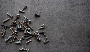 Eski civatalar ve fındıklar koyu gri beton arka planda. Çerçeve ya da sınır. Kopyalama alanı olan desenli arkaplan.