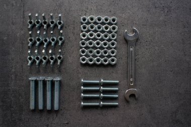 Anahtar aleti, eski fındıklar ve civatalar farklı boyutlarda üst görüntü fotoğrafı. Fotokopi alanı olan gri desenli beton arka plan. Tamirci aletleri resmi kapatır. Ev yenileme konsepti. 