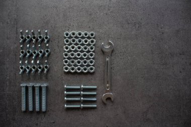 Anahtar aleti, eski fındıklar ve civatalar farklı boyutlarda üst görüntü fotoğrafı. Fotokopi alanı olan gri desenli beton arka plan. Tamirci aletleri resmi kapatır. Ev yenileme konsepti. 