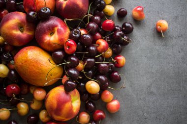 Sulu yaz meyveleri ve meyvelerden yapılmış renkli çerçeve ya da sınır. Kirazlı, şeftalili ve elmalı fotoğraf. Gri desenli arka plan ve fotokopi alanı. Sağlıklı yeme kavramı. 