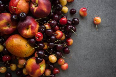 Sulu yaz meyveleri ve meyvelerden yapılmış renkli çerçeve ya da sınır. Kirazlı, şeftalili ve elmalı fotoğraf. Gri desenli arka plan ve fotokopi alanı. Sağlıklı yeme kavramı. 