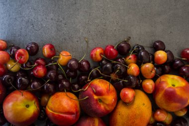 Sulu yaz meyveleri ve meyvelerden yapılmış renkli çerçeve ya da sınır. Kirazlı, şeftalili ve elmalı fotoğraf. Gri desenli arka plan ve fotokopi alanı. Sağlıklı yeme kavramı. 