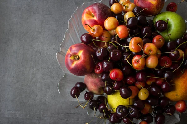 玻璃瓶里有多汁的夏天水果 灰色混凝土背景 有复制空间 甜樱桃 芒果和苹果顶部的照片 健康饮食概念 — 图库照片