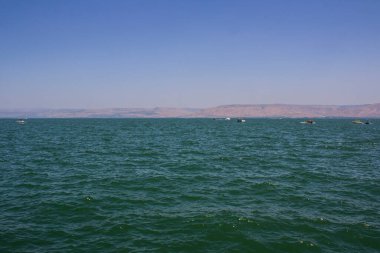 Deniz manzaralı güzel bir fotoğraf. Sudaki ahşap kayıklar, mavi gökyüzü ufuktaki tepeler ve sakin Akdeniz suyu. Ortadoğu doğası. İsrail yaz manzarası. 